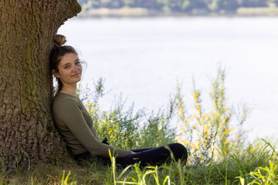 Young brunette woman sitting in green forest enjoys the silence and beauty of nature 