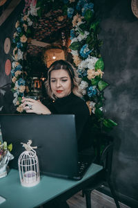 Woman looking at camera while sitting on table