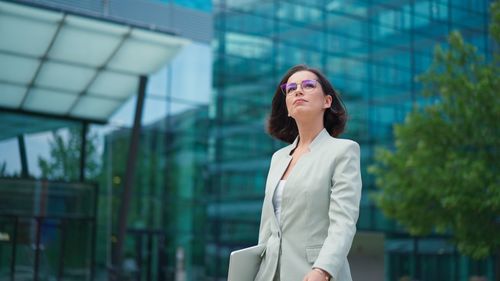 Calm businesswoman looking time on hand watch while going to the work after break