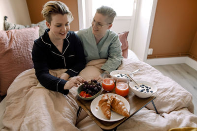 Lesbian couple enjoying breakfast in bed at home