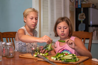 Two young girls make home made pickles out of fresh little pickling cucumbers