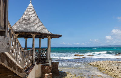 Lifeguard hut on beach against blue sky