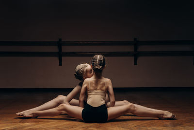 Young ballerinas doing the splits, stretching their legs in a pose on stage, in the studio.