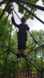 Low angle view of girl balancing on jungle gym at playground