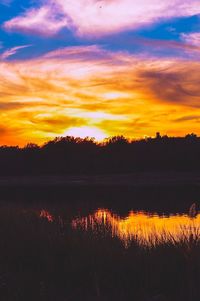 Scenic view of lake against cloudy sky during sunset