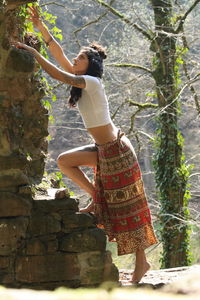Side view of woman standing by tree