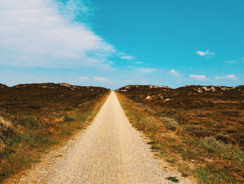 Road amidst field against sky