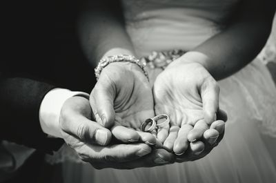 Midsection of couple holding rings