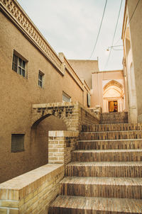 Low angle view of steps amidst buildings against sky