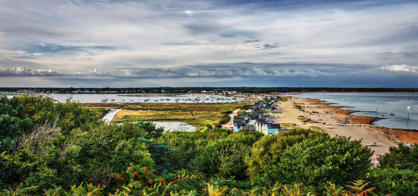 Houses on shore at mudeford against cloudy sky