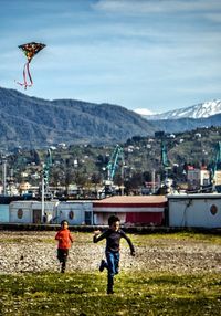 Full length of man with arms outstretched against mountain range