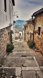 Steps amidst houses against sky