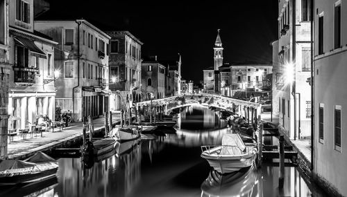 Boats moored on canal in city at night