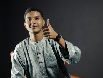 Portrait of young man standing against black background