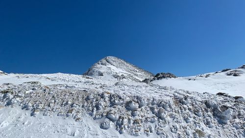 Scenic view of snow covered mountain against blue sky