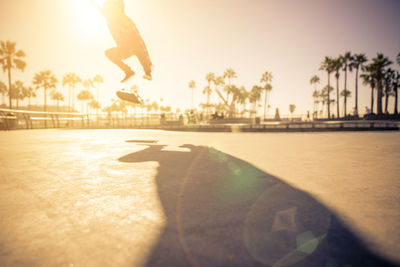 Surface level of man skateboarding on street against sky during sunset