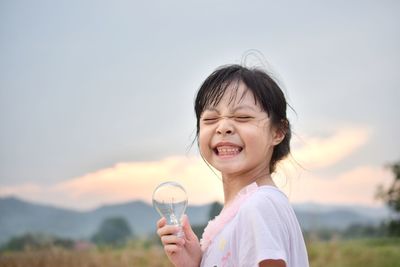 Portrait of smiling woman holding glass against sky
