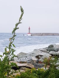 Lighthouse by sea against sky