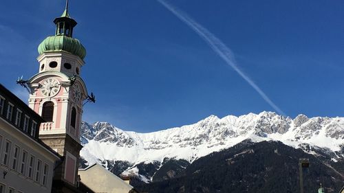 Low angle view of snow covered mountain against blue sky