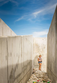 Young woman standing amidst concrete wall