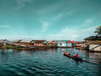 People in boat river against sky