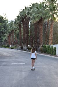 Rear view of woman skateboarding on road