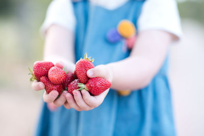 Child girl holding fresh strawberry outdoors closeup. healthy eating. childhood.