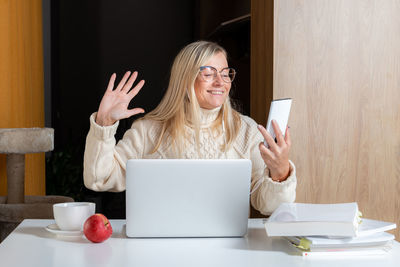 Young woman using mobile phone while sitting on table