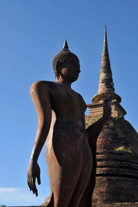 Low angle view of statue against temple building against clear sky