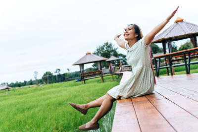 Woman with arms raised on field against sky