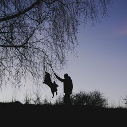 Silhouette man standing on field against sky during sunset