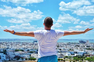 Rear view of man standing by cityscape against sky