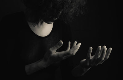 Midsection of woman standing against black background