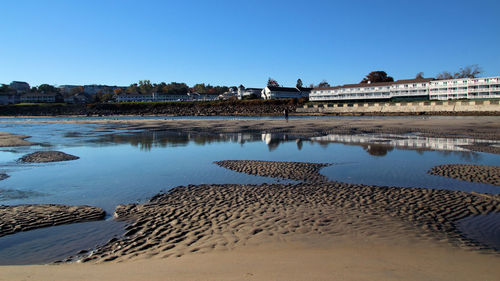 Reflection of man on beach against clear blue sky