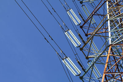 Low angle view of electricity pylon against clear blue sky