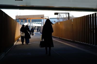 Rear view of people walking on railroad station