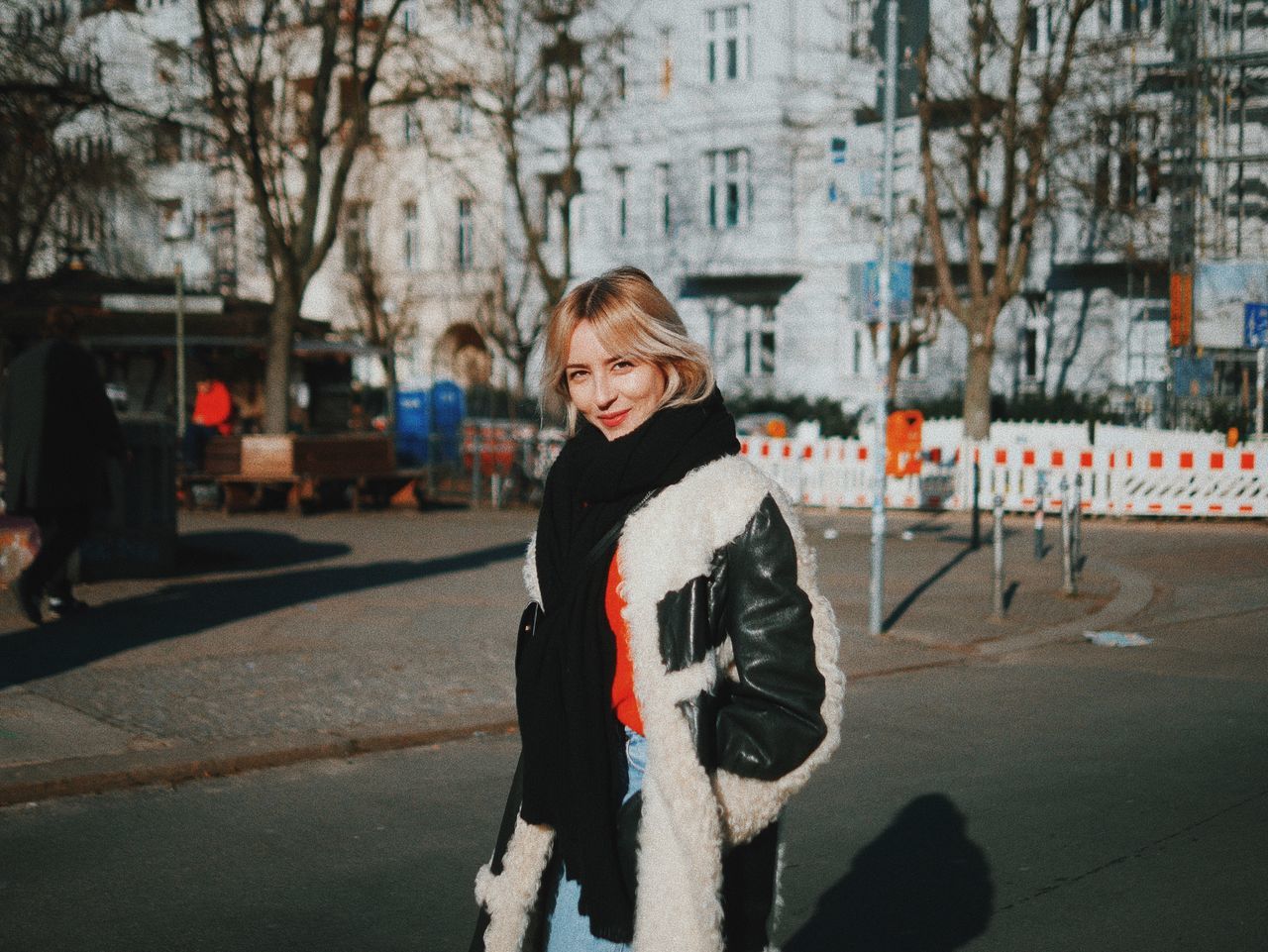 winter, real people, one person, outdoors, looking at camera, building exterior, front view, bare tree, cold temperature, warm clothing, architecture, smiling, tree, snow, happiness, built structure, portrait, day, city, people