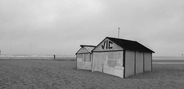 Hut on beach by sea against sky