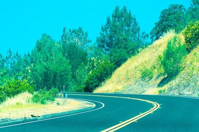 Road amidst trees against clear sky