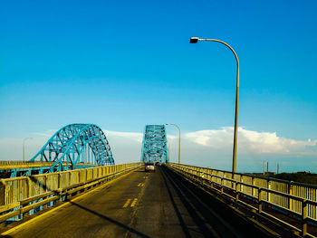 Street lights on bridge against blue sky