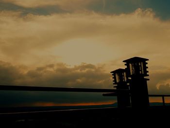 Silhouette built structure by sea against sky during sunset