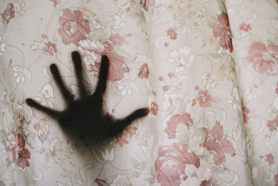 Cropped hand of woman seen through curtain