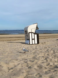 Hooded beach chair on shore against sky