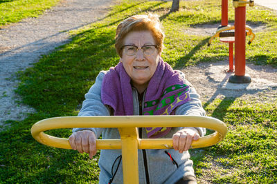 Elderly woman practices sport moving the wheels in a bio-healthy park, at sunset