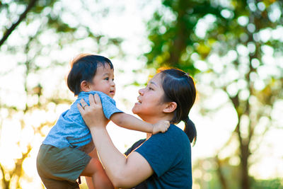 Side view of mother and daughter against trees