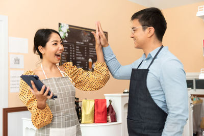 Young woman using digital tablet while standing against white background