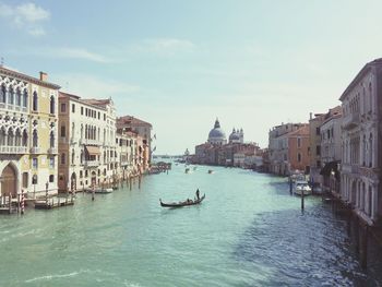 Man sailing gondola in canal in city