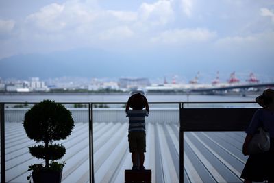 Rear view of man and woman walking on bridge in city