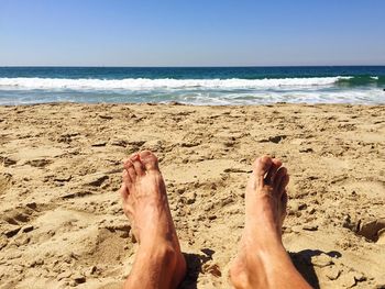 Low section of man relaxing on beach