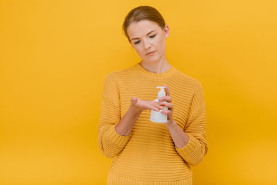 Full length of a smiling young woman against yellow background